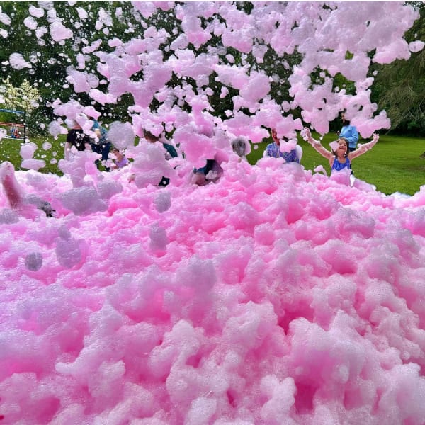 Kids playing in a mountain of vibrant pink foam at a Color Hype foam party