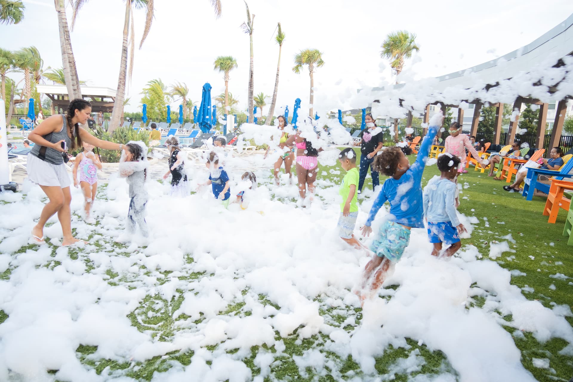 Kids and families laughing and playing in a mountain of white foam at a resort foam party