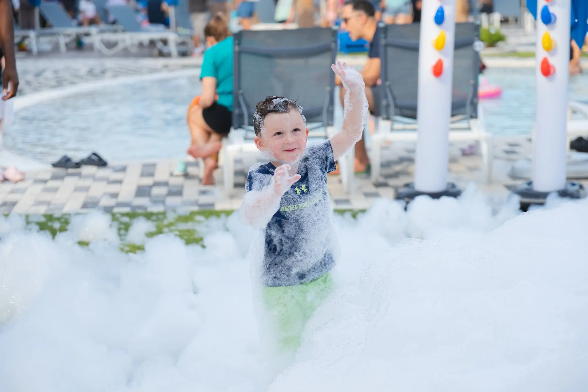 Child waving happily while playing in deep white foam