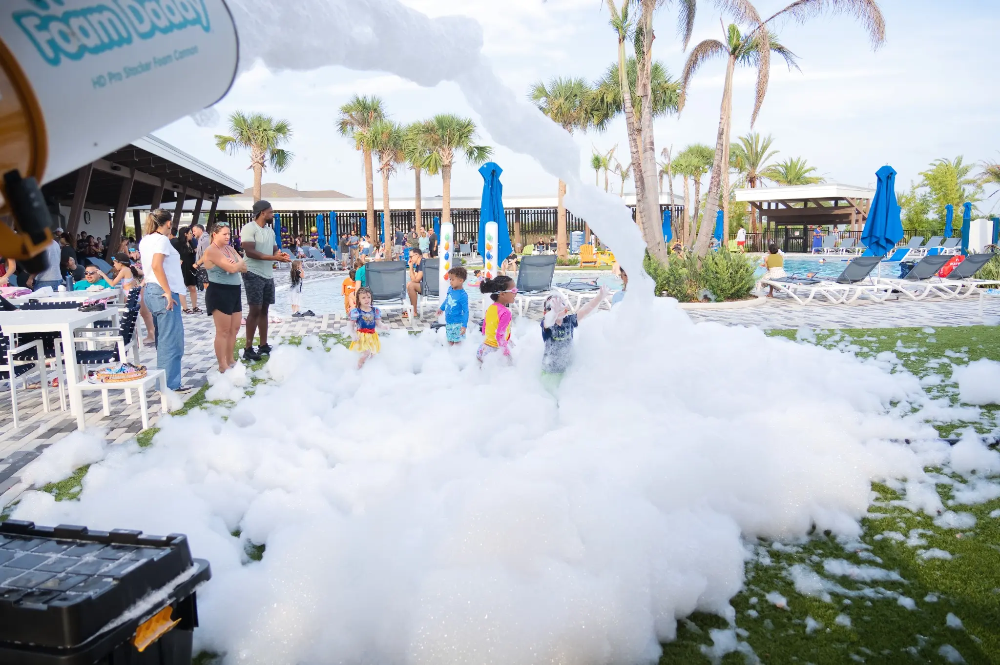 Foam cannon spraying a thick wave of foam across a poolside lawn
