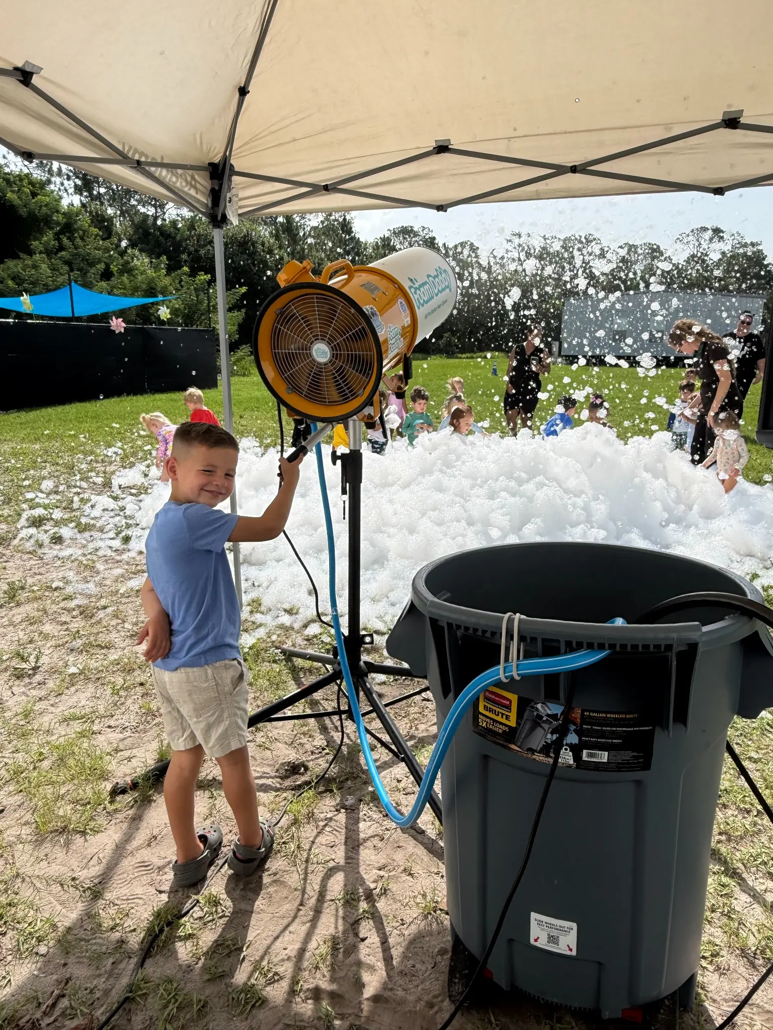 Professional foam cannon set up under a shade tent with a water supply bin
