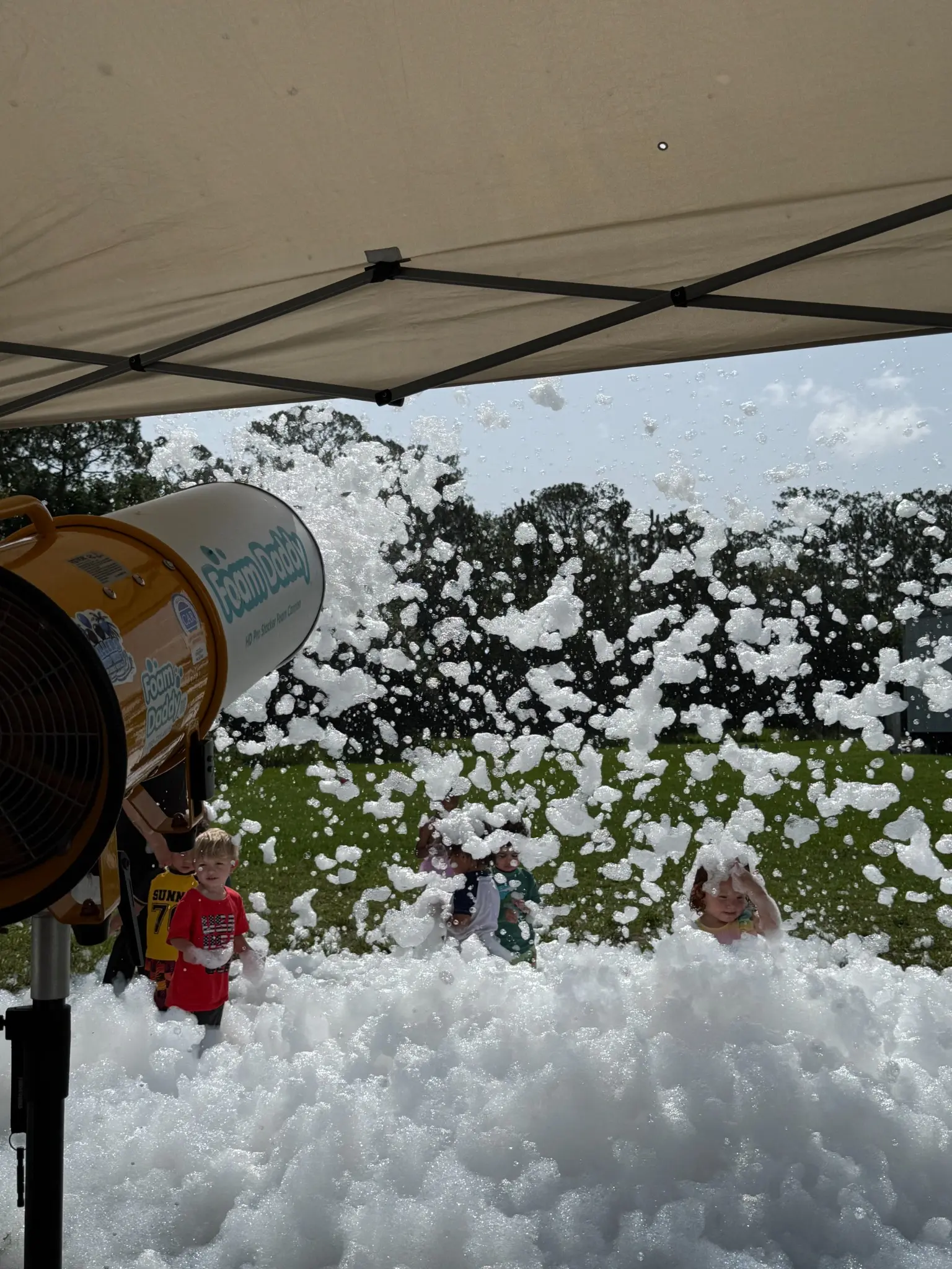 Foam Daddy cannon spraying foam toward guests playing on a grass field