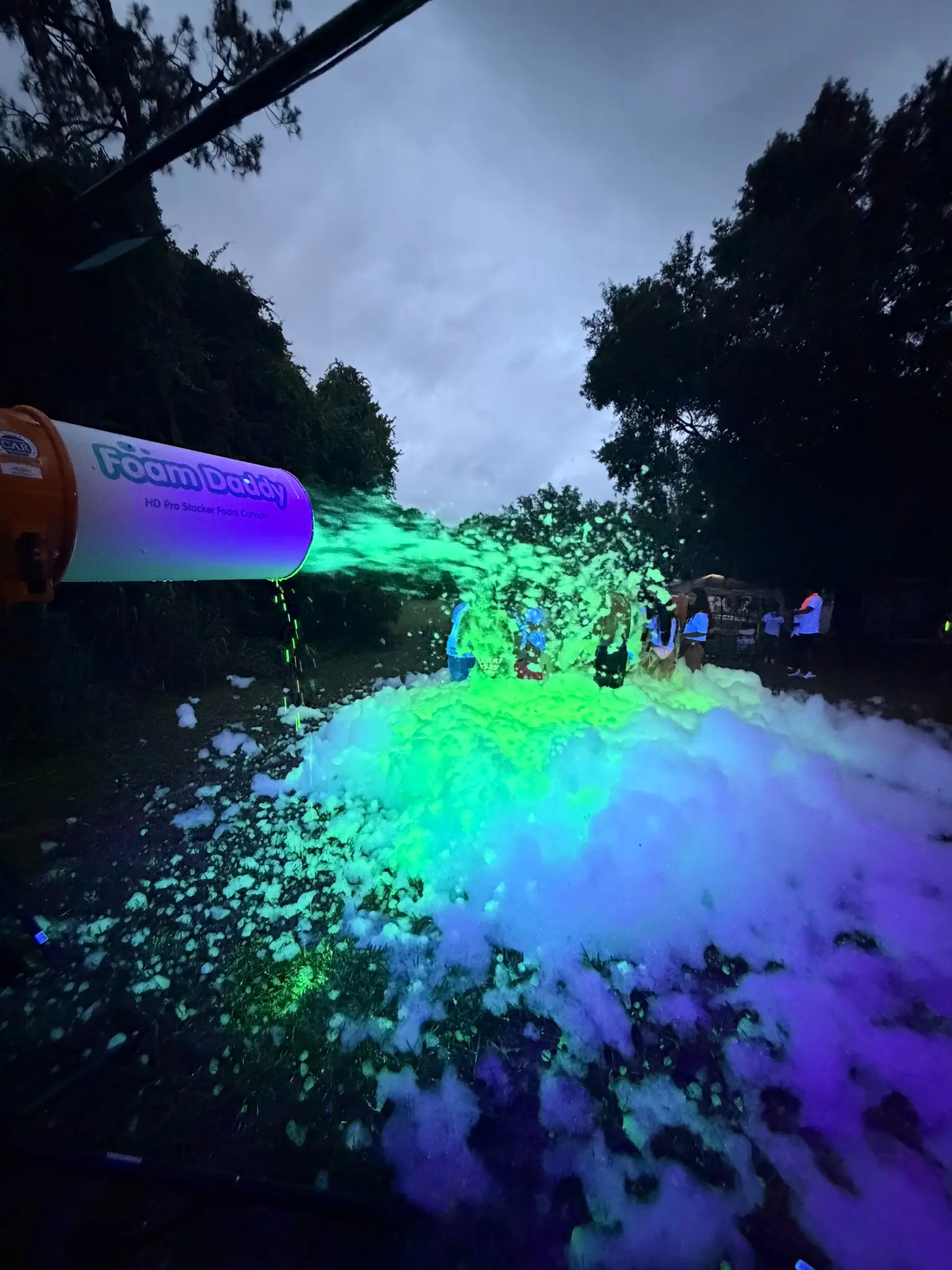 Glowing neon foam sprayed from a professional foam cannon at a nighttime glow foam party