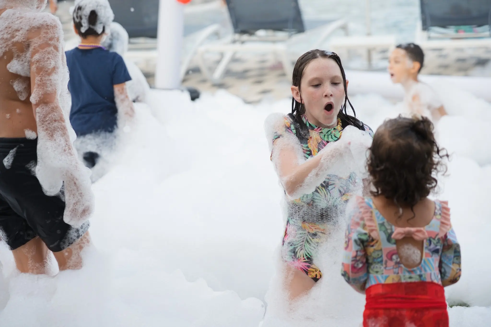 Kids laughing and playing in white foam at a Central Florida backyard foam party
