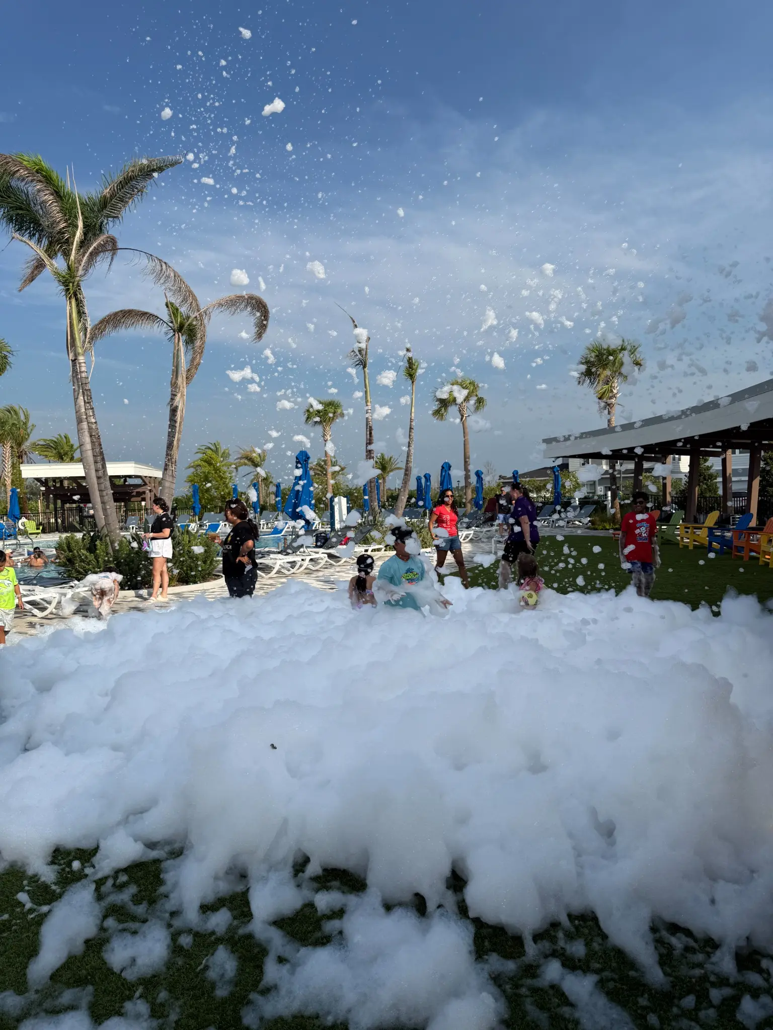 Mountain of foam beside a resort pool deck with palm trees overhead